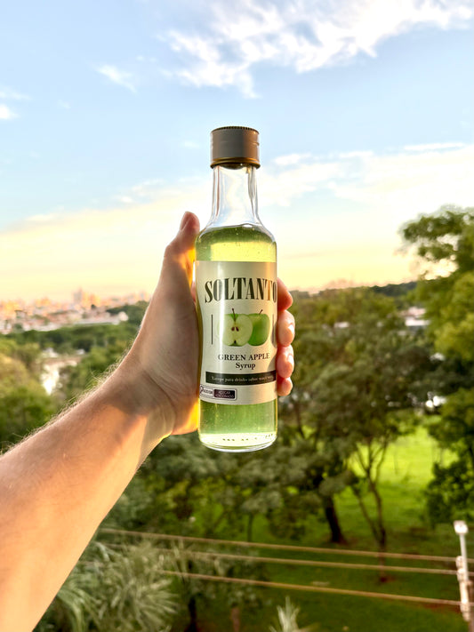 Xarope de maçã verde sendo segurado na mão